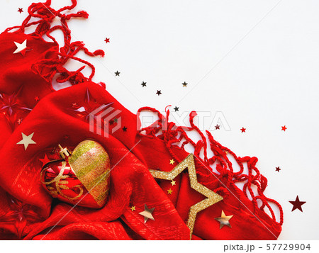 Christmas and New Year background. Bright red scarf with golden stars and confetti on white background. Folded warm accessory with copy space. Christmas and New Year background. Bright red scarf with golden stars and confetti on white background. Folded warm accessory with copy space. 57729904