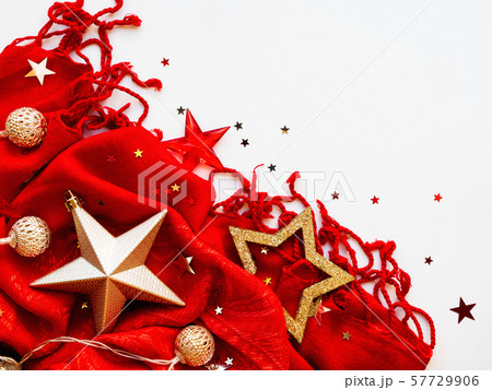 Christmas and New Year background. Bright red scarf with golden stars and confetti on white background. Folded warm accessory with copy space. Christmas and New Year background. Bright red scarf with golden stars and confetti on white background. Folded warm accessory with copy space. 57729906