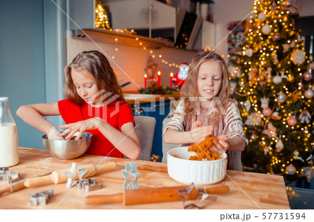 Little girls making Christmas gingerbread house at fireplace in decorated living room. 57731594