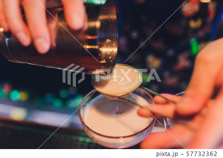 A bartender makes a cocktail over the marble bar counter. 57732362