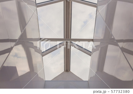 Looking up to the blue cloudy sky through modern square ceiling window. 57732380