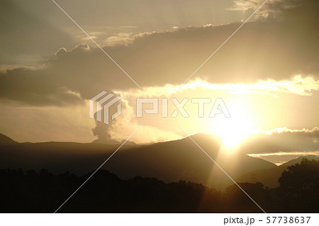 煙を吐く阿蘇山と日の出の風景の写真素材