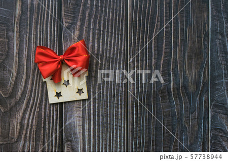 Christmas background with wooden decorative gift and red bow on the old wooden board 57738944