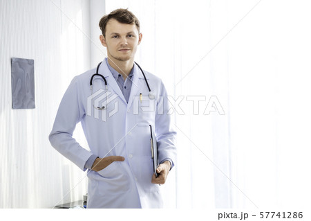 Happy man doctor possing and wearing a stethoscope Happy man doctor possing and wearing a stethoscope 57741286