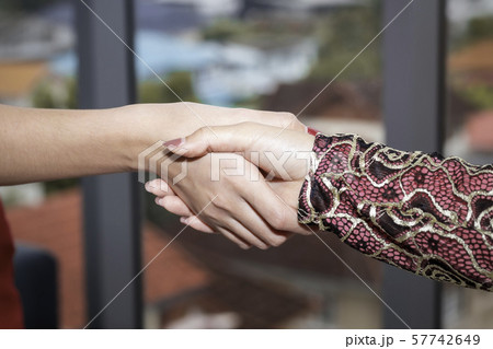 Young beautiful Muslim woman shaking hand with 57742649