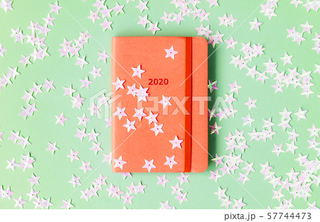 Orange diary for 2020 on a mint background strewn with light pink stars. 57744473