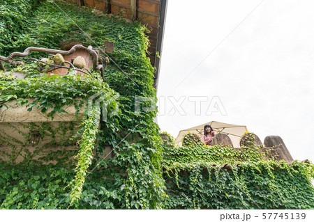 A Japanese woman walks through the castle in the forest. The woman wore a hat. 57745139