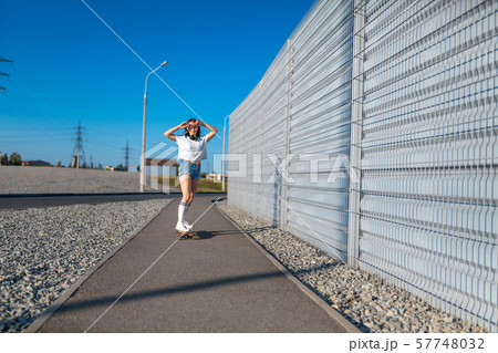 stylish girl in white stockings ride on longboard 57748032