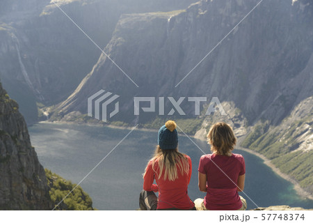 Two sitting women are looking for mountain lake Two sitting women are looking for mountain lake 57748374