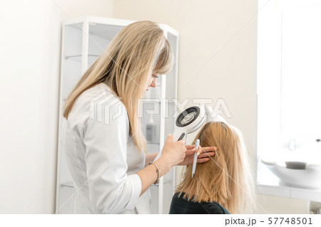 The doctor trichologist dermatologist examines the The doctor trichologist dermatologist examines the 57748501