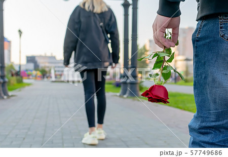 red rose flower in the hand of the guy on the background of the girl 57749686