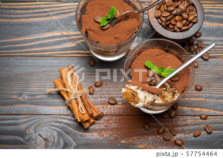 Portion of Classic tiramisu dessert in a glass and savoiardi cookies on wooden background 57754464