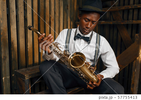 Black jazz musician sitting with saxophone 57755413