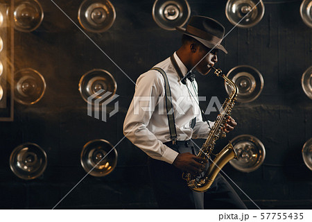 Black jazzman in hat plays the saxophone on stage 57755435