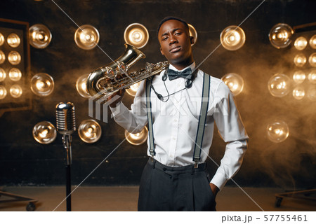 Black jazz performer poses with saxophone on stage 57755461