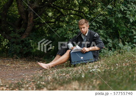 Businessman sitting on the ground on desert island Businessman sitting on the ground on desert island 57755740