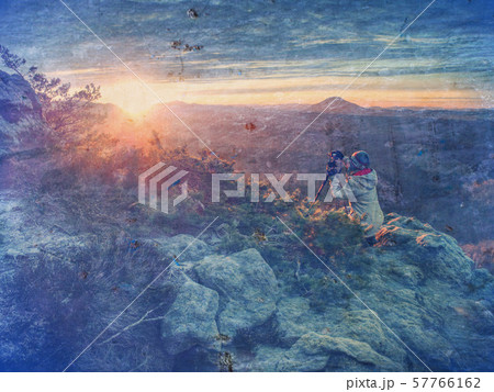 Tourist with camera shoots sunrise while standing Tourist with camera shoots sunrise while standing 57766162