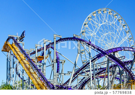 Rollercoaster and Ferris wheel against blue sky. 57769838