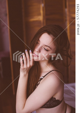 Young attractive woman with long dark hair in black lace lingerie on a bed. Boudoir photo of a young girl Young attractive woman with long dark hair in black lace lingerie on a bed. Boudoir photo of a young girl 57774293