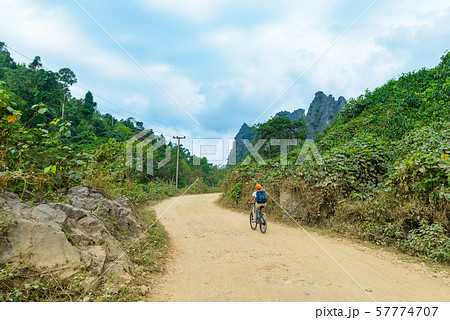 Woman riding mountain bike on dirt road in scenic 57774707