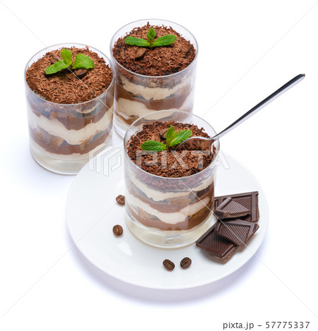 Classic tiramisu dessert in a glass cup on the plate and pieces of chocolate on white background 57775337