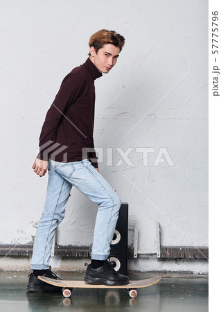 cool handsome man in stylish sweater stands on his skateboard 57775796