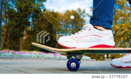Teenage girl rides on a skateboard in the autumn park. 57776107