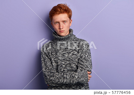 Freezing young man in gray warm sweater holding hands folded Freezing young man in gray warm sweater holding hands folded 57776456