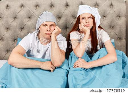 Sleepy tired couple sitting in bed canot wake up in morning 57776519