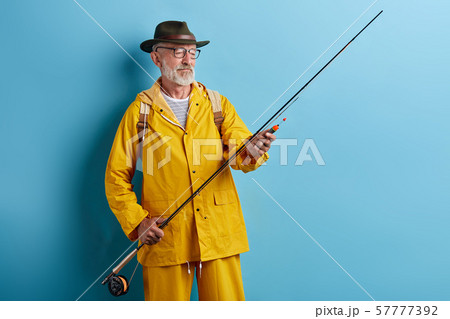 old man in glasses wearing stylish yellow coat preparing rod for fishing old man in glasses wearing stylish yellow coat preparing rod for fishing 57777392