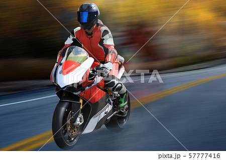 Motorcycle racer in helmet racing at high speed Motorcycle racer in helmet racing at high speed 57777416