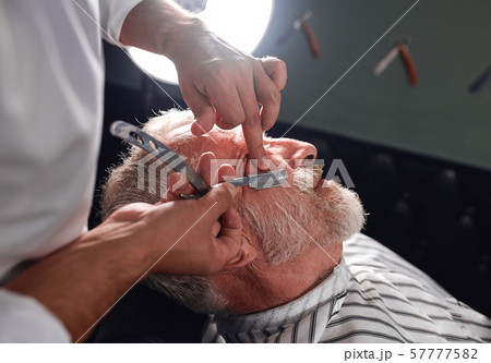 stylist touching his client's cheeck with finger, shaving hairs 57777582