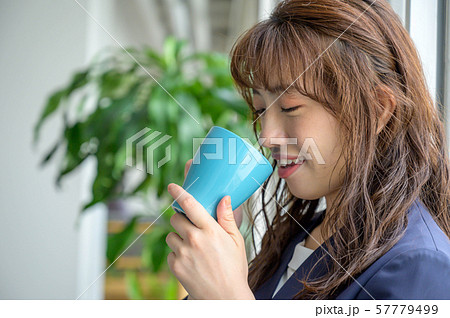 オフィスで飲み物片手に休憩する女性 57779499