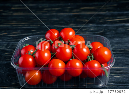 Cherry tomatoes in the plastic box on the wooden 57780072