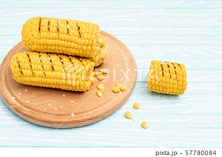 Grilled hot Corn cob lies on cutting board blue Grilled hot Corn cob lies on cutting board blue 57780084