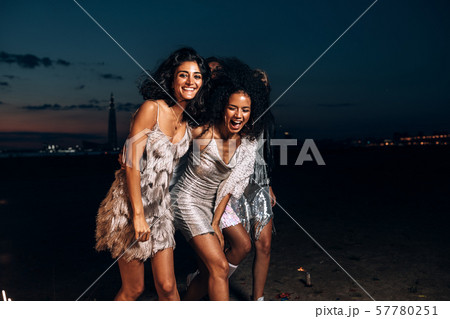 Group of happy girlfriends dancing between fireworks at night 57780251