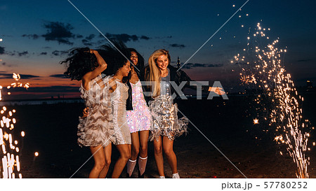 Group of happy girlfriends dancing between fireworks at night 57780252