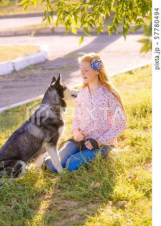 Cute teen girl with red long hair walks with her husky breed dog in the autumn park. Children and dogs. Autumn mood 57780494