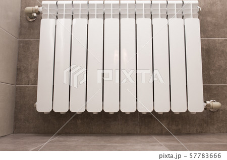White radiator in the bathroom close-up. Heating. Tiled gray wall. White radiator in the bathroom close-up. Heating. Tiled gray wall. 57783666