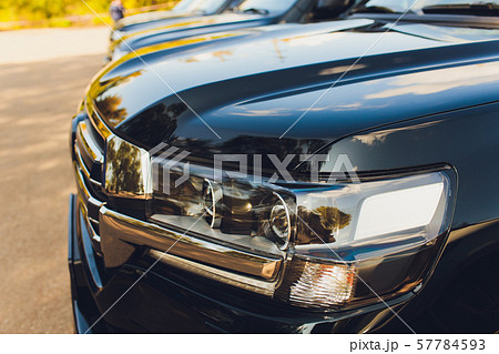 Closed up headlight of white SUV with raindrop on car hood. 57784593