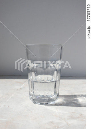 Half full glass with mineral water on table and 57785750