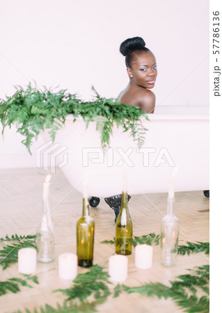 Woman bathing in a tub full of foam. Beautiful african american bride in decorated bath Woman bathing in a tub full of foam. Beautiful african american bride in decorated bath 57786136