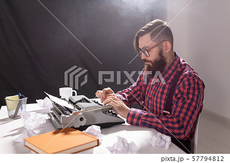 People and technology concept - Writer sits at a table surrounded by scraps of paper People and technology concept - Writer sits at a table surrounded by scraps of paper 57794812
