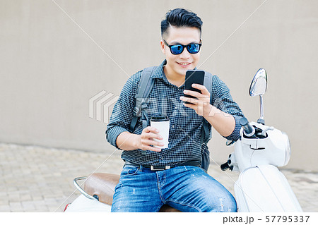 Smiling man checking notifications on smartphone 57795337