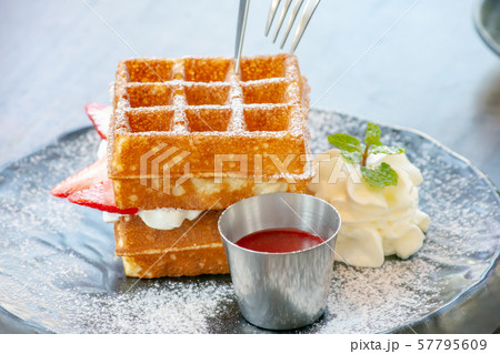 Waffle Strawerry fresh cream in the black plate on wooden table. 57795609