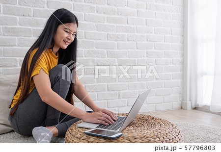 Asian female sit with knees up on floor using 57796803