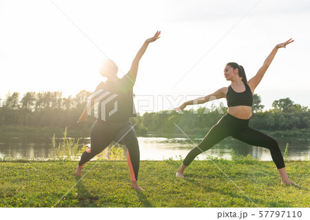 Harmony and healthy lifestyle concept - Young slim women in sportswear practicing yoga outdoors. Harmony and healthy lifestyle concept - Young slim women in sportswear practicing yoga outdoors. 57797110