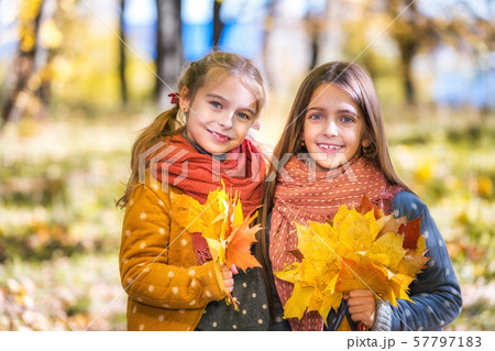 Two cute smiling 8 years old girls posing together in a park on a sunny autumn day. Two cute smiling 8 years old girls posing together in a park on a sunny autumn day. 57797183