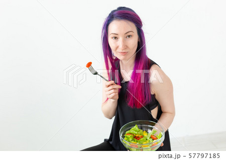 Top view of a young asian hipster girl eating a light vegetable salad after a workout at her home Top view of a young asian hipster girl eating a light vegetable salad after a workout at her home 57797185