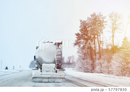 Truck with cargo tank on a slippery snow winter road outside the city, back view Truck with cargo tank on a slippery snow winter road outside the city, back view 57797830